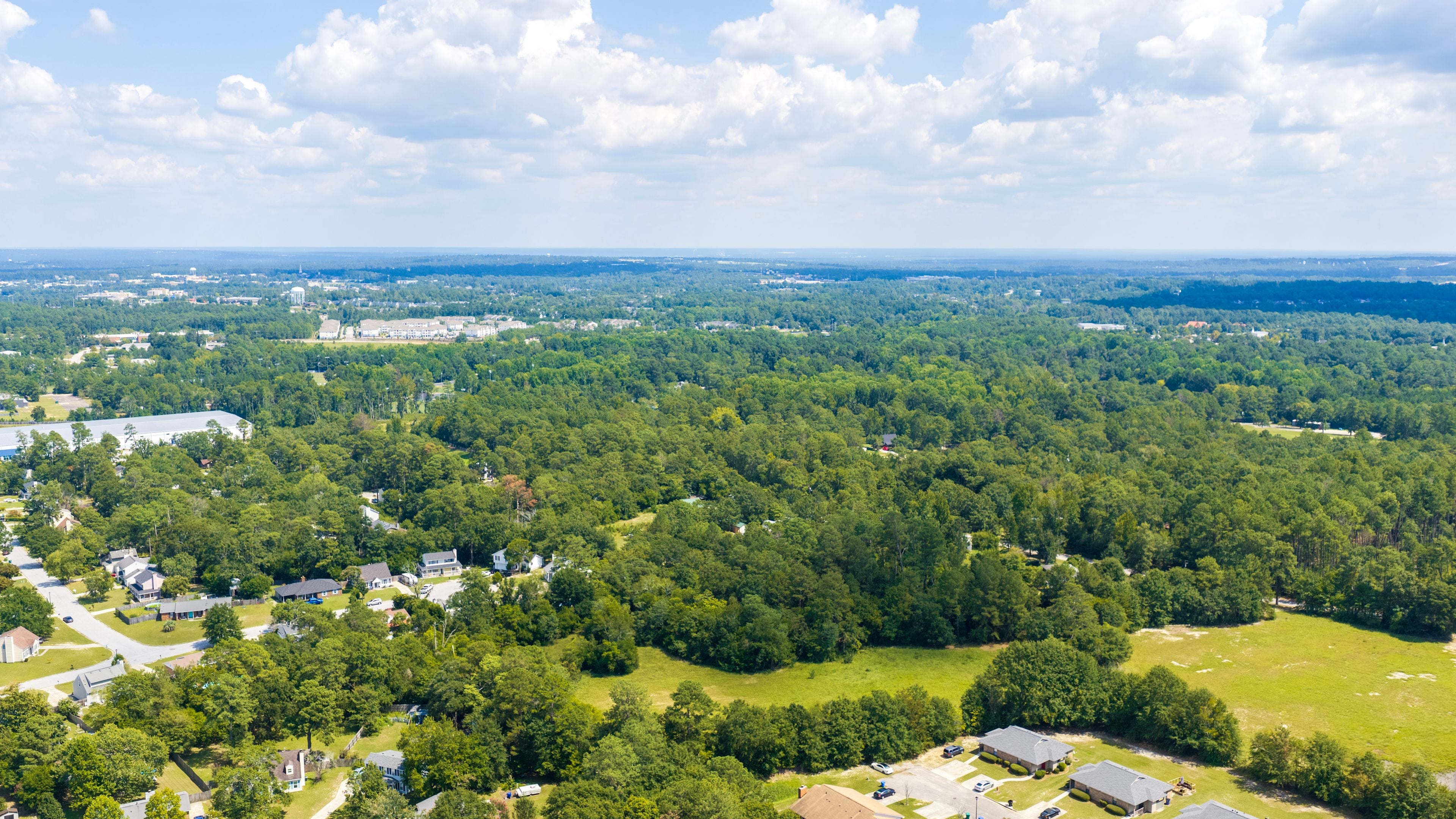 A residential area with houses, roads, and dense forest.