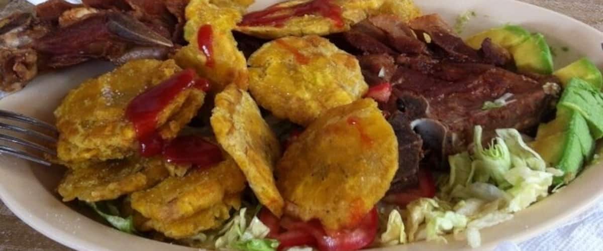 A plate of food with fried plantains, avocado slices, and meat.