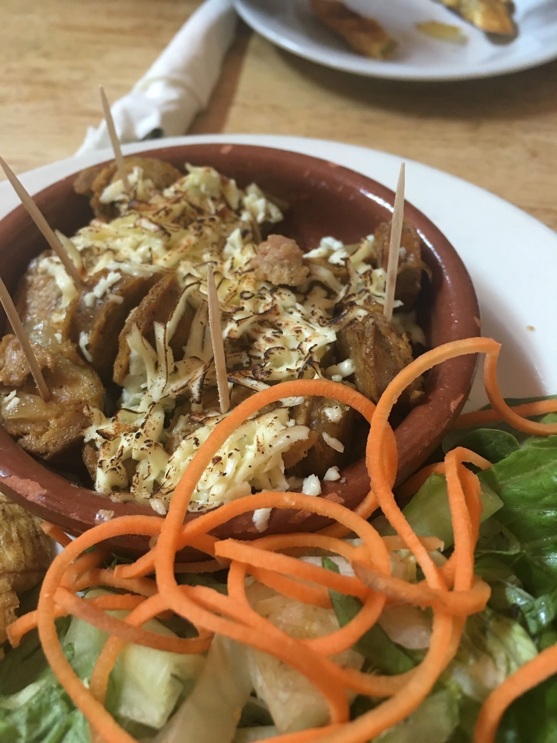 A bowl of food with grilled meat, shredded vegetables, and carrot strips.