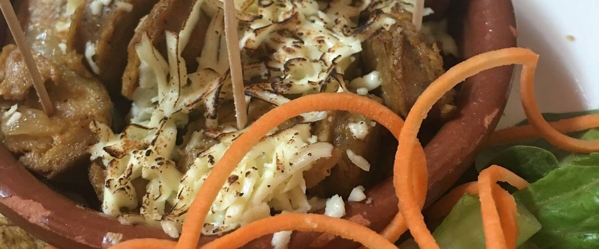 A bowl of food with grilled meat, shredded vegetables, and carrot strips.