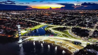 Un paisaje urbano al atardecer con un parque costero destacado y un monumento alto.