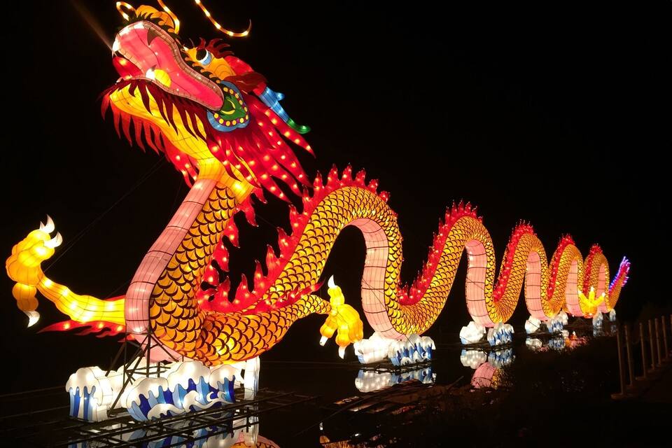 Una gran escultura iluminada de un dragón por la noche.