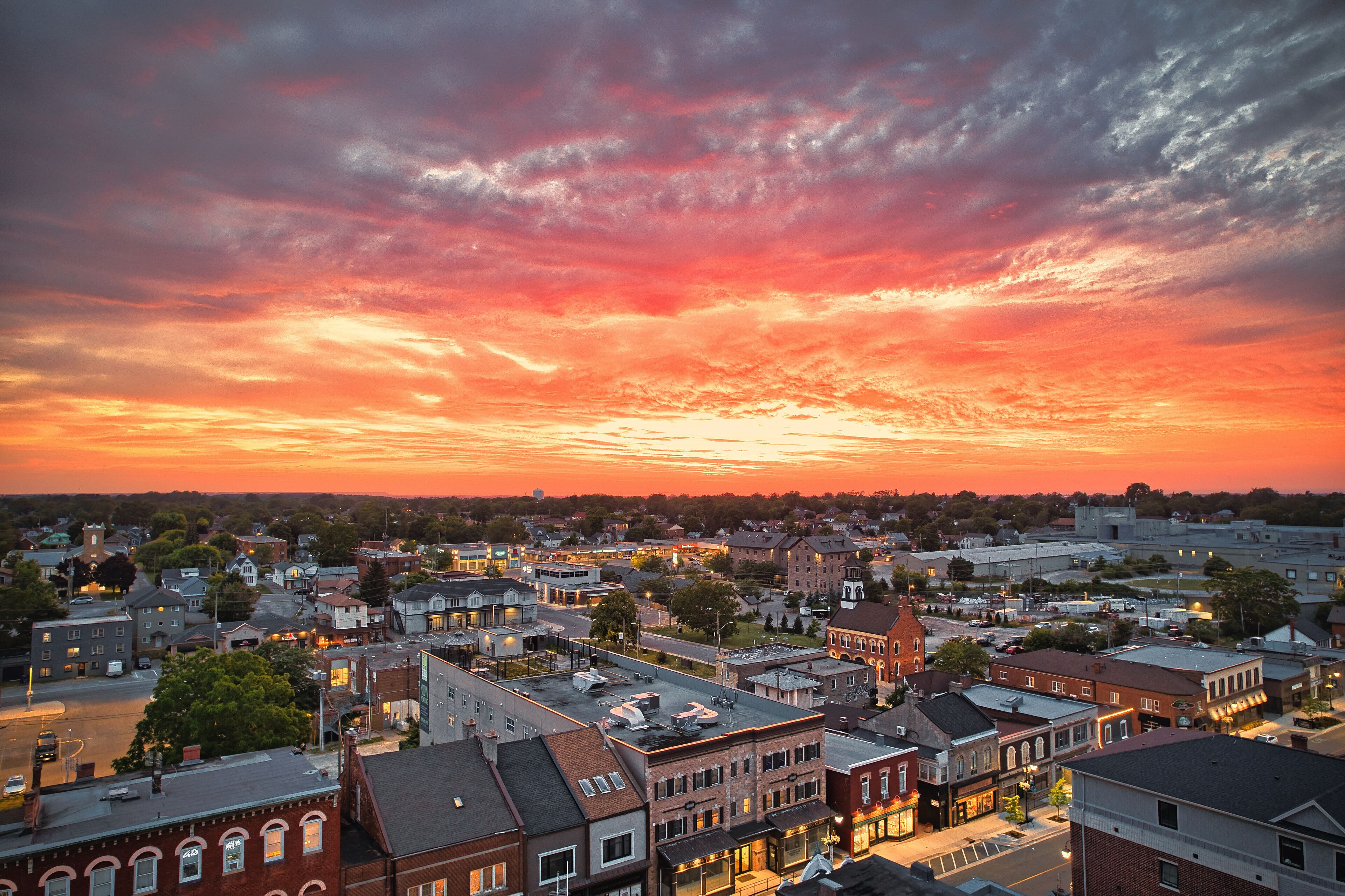 A town at sunset with a vibrant sky and illuminated buildings.