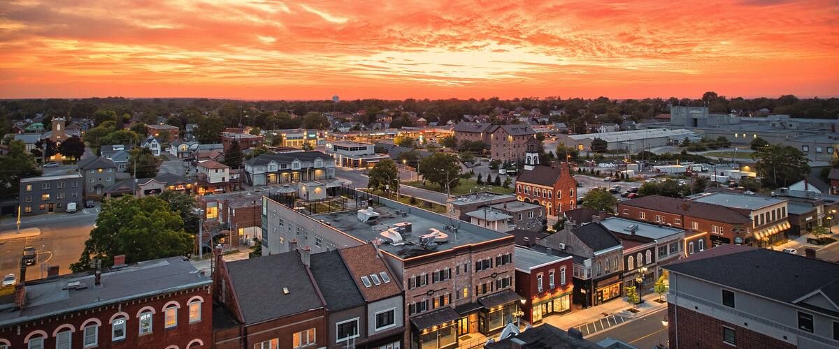A town at sunset with a vibrant sky and illuminated buildings.