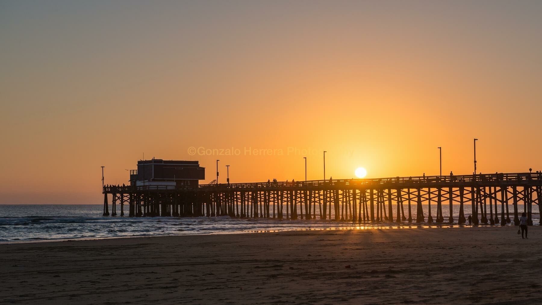 A pier extending into the ocean at sunset.
