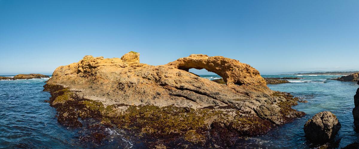 A rocky coastal landscape with a prominent arch formation.