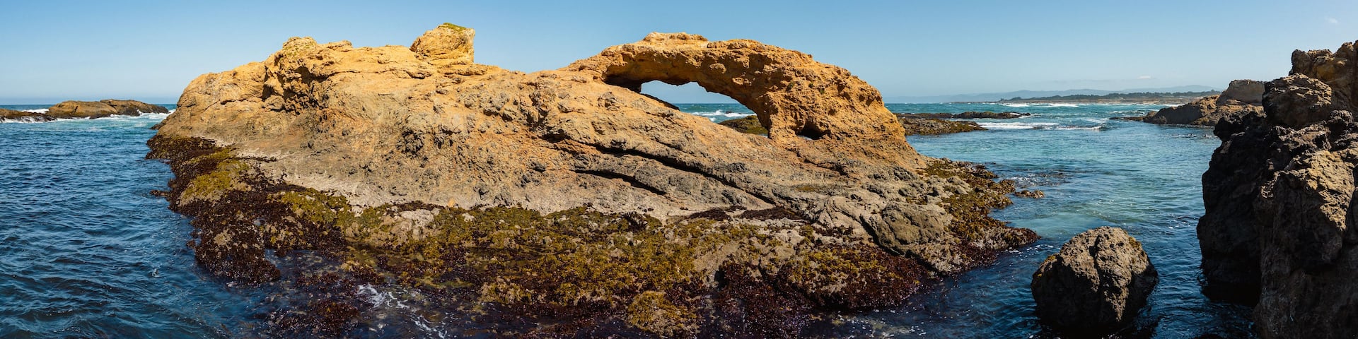 A rocky coastal landscape with a prominent arch formation.