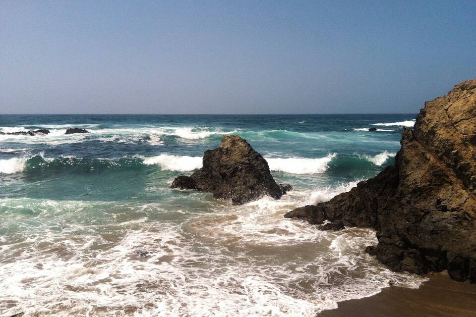 Une côte rocheuse où les vagues s’écrasent sur le rivage.
