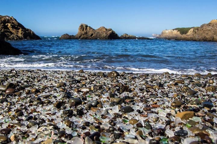 A pebble beach with a rocky shoreline and calm sea.