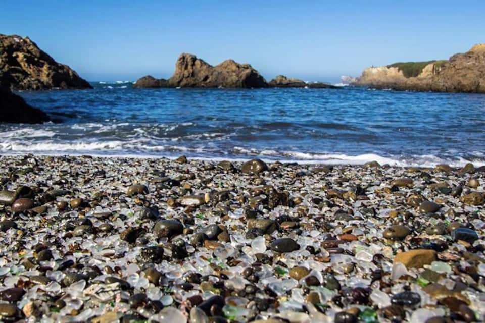A pebble beach with a rocky shoreline and calm sea.