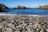 Una spiaggia di ciottoli con un litorale roccioso e mare calmo.