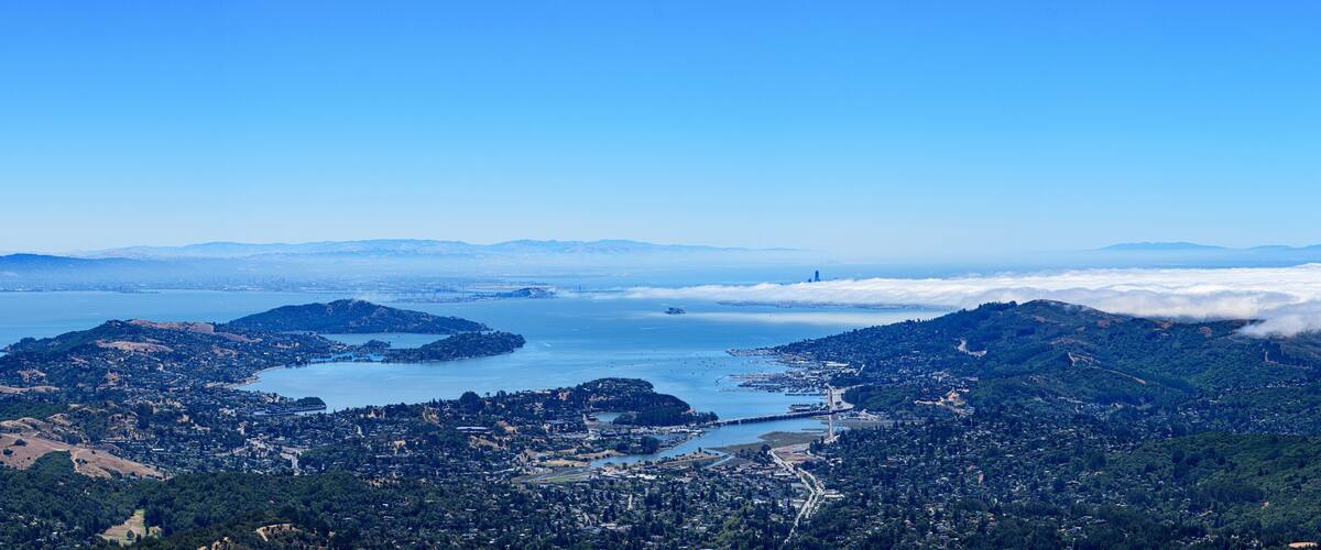 A coastal city with a bay, mountains, and a bridge.
