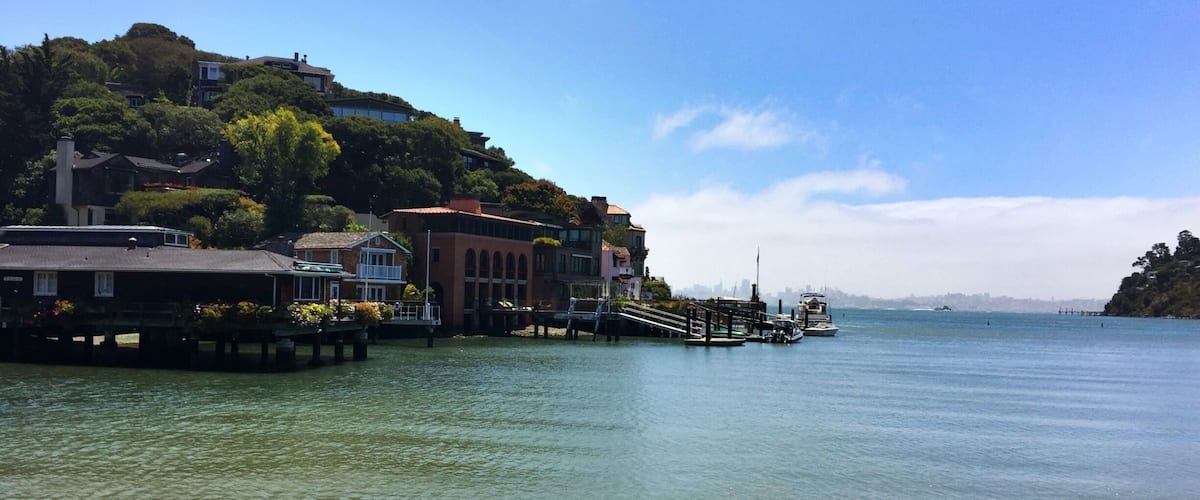 A waterfront with houses on stilts, a pier, and a clear blue sky.