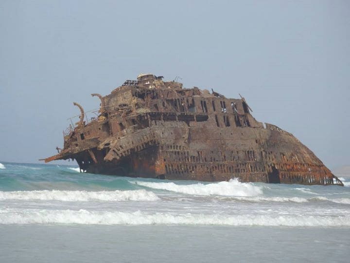 A large, rusted shipwreck in the ocean.