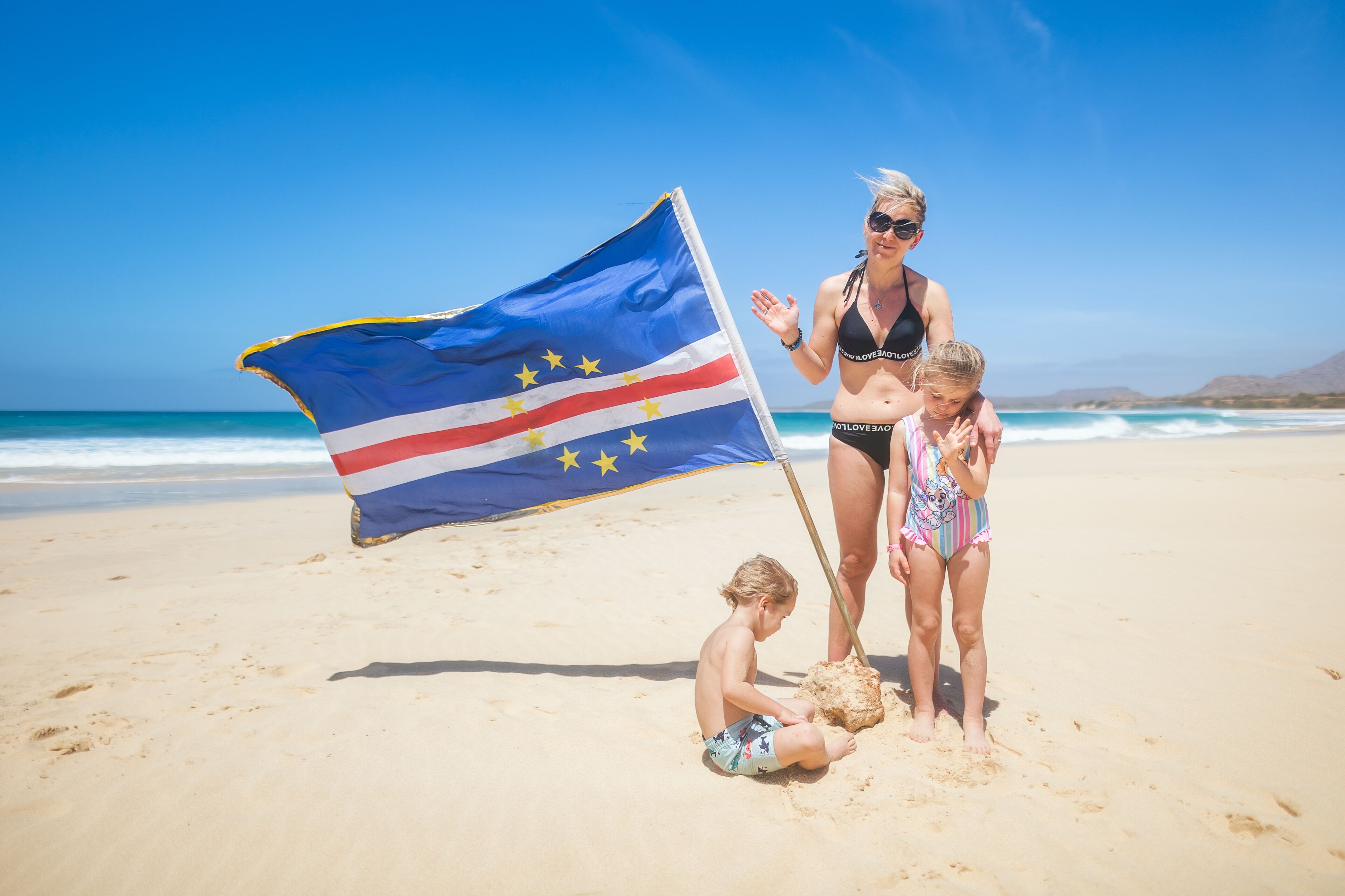 Mum with their children on Santa Monica beach on Boa Vista island with Cape Verde flag