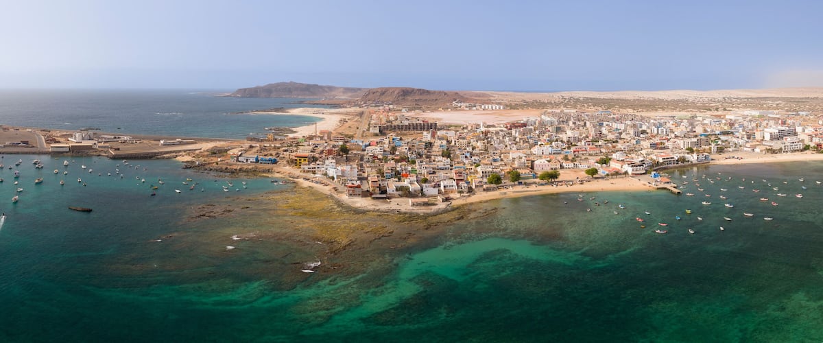 An aerial view of a coastal town with a harbor, boats, and buildings.