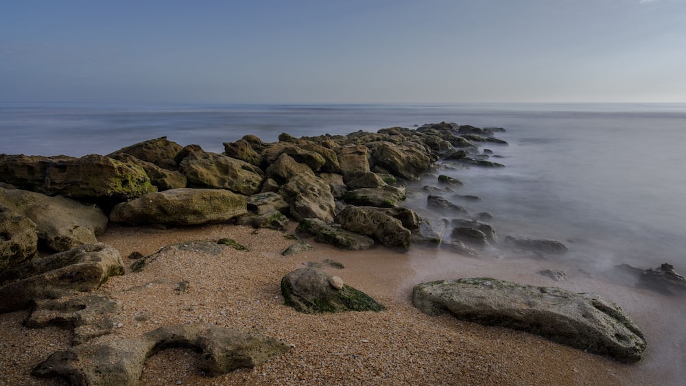 Un rivage rocheux, une mer calme et un ciel dégagé.