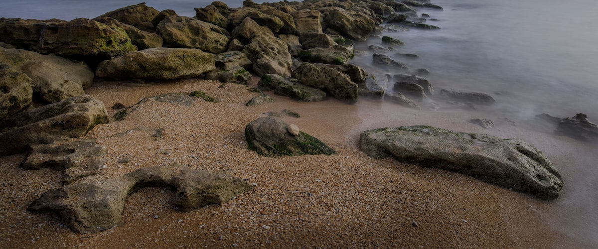 A rocky shoreline with a calm sea and clear sky.