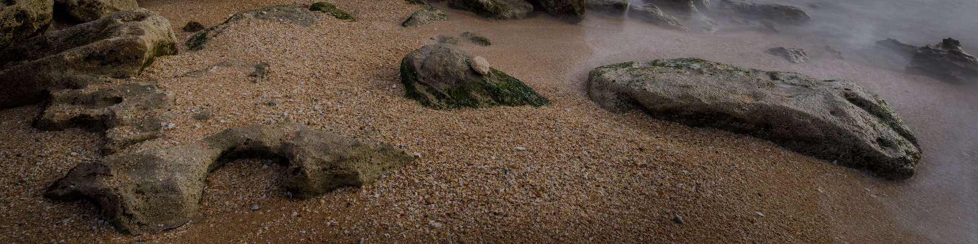 A rocky shoreline with a calm sea and clear sky.