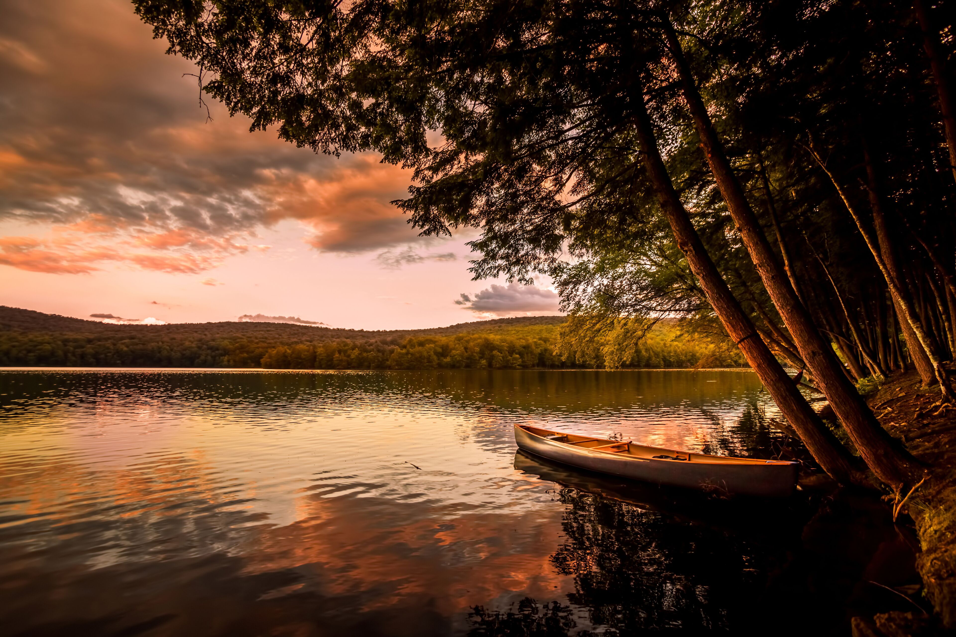 Canoe on the lake at sunset. Warm sunset colors spill over Mongaup Pond, the largest lake in the Catskills. One of the most popular summer vacation and camping destination in New York