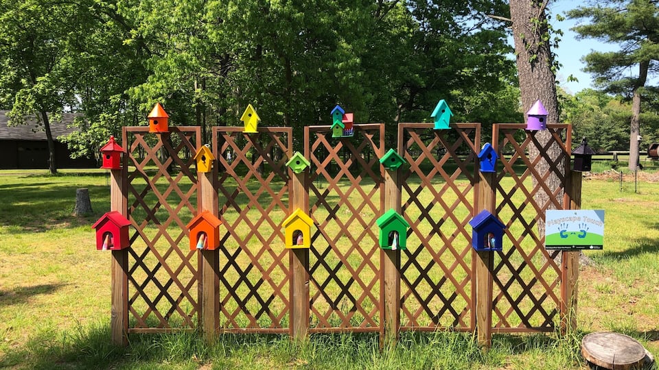 A wooden lattice fence with colorful birdhouses attached to it.