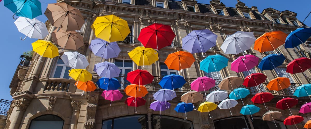 A historic building with colorful umbrellas hanging from the facade.