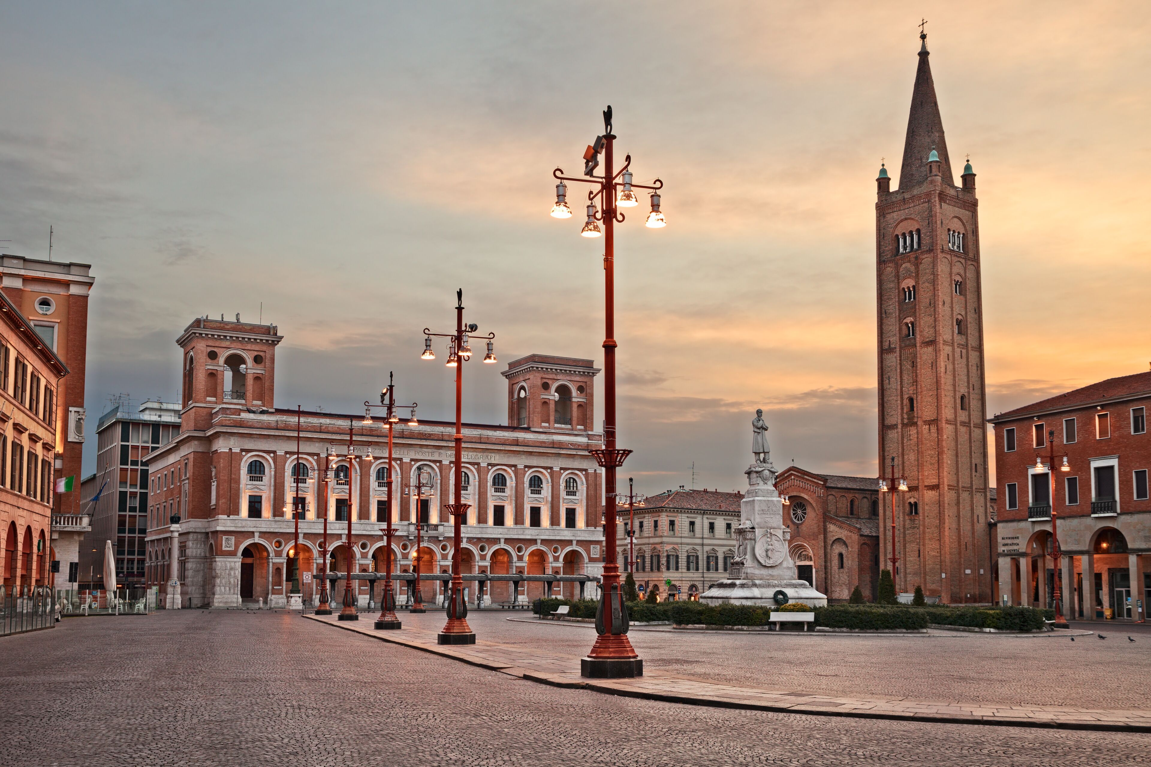 A historic square with a prominent church tower, a fountain, and classical architecture.