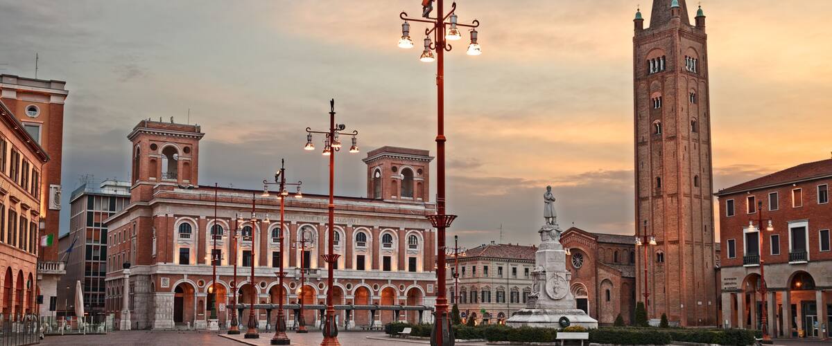 A historic square with a prominent church tower, a fountain, and classical architecture.
