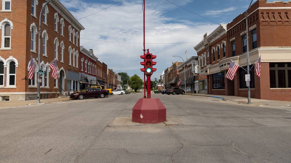 A street with brick buildings, American flags, and a traffic light.