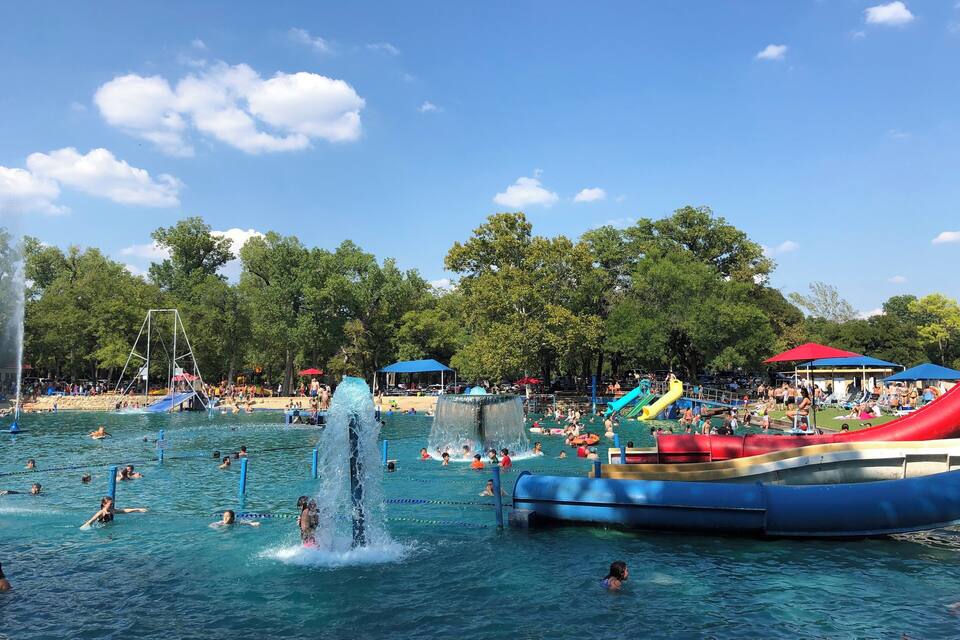 A water park with slides, a water fountain, and people swimming.