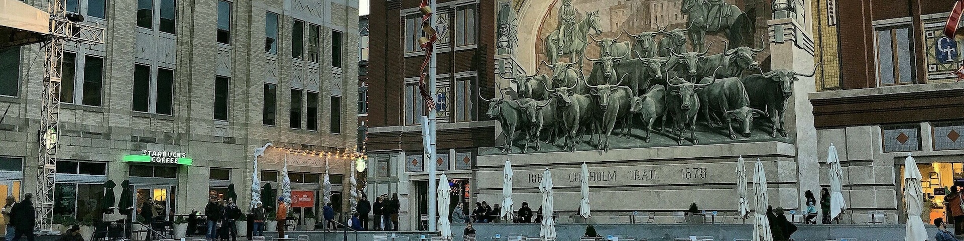 Una plaza urbana con una fuente, un mural de toros y un Starbucks.