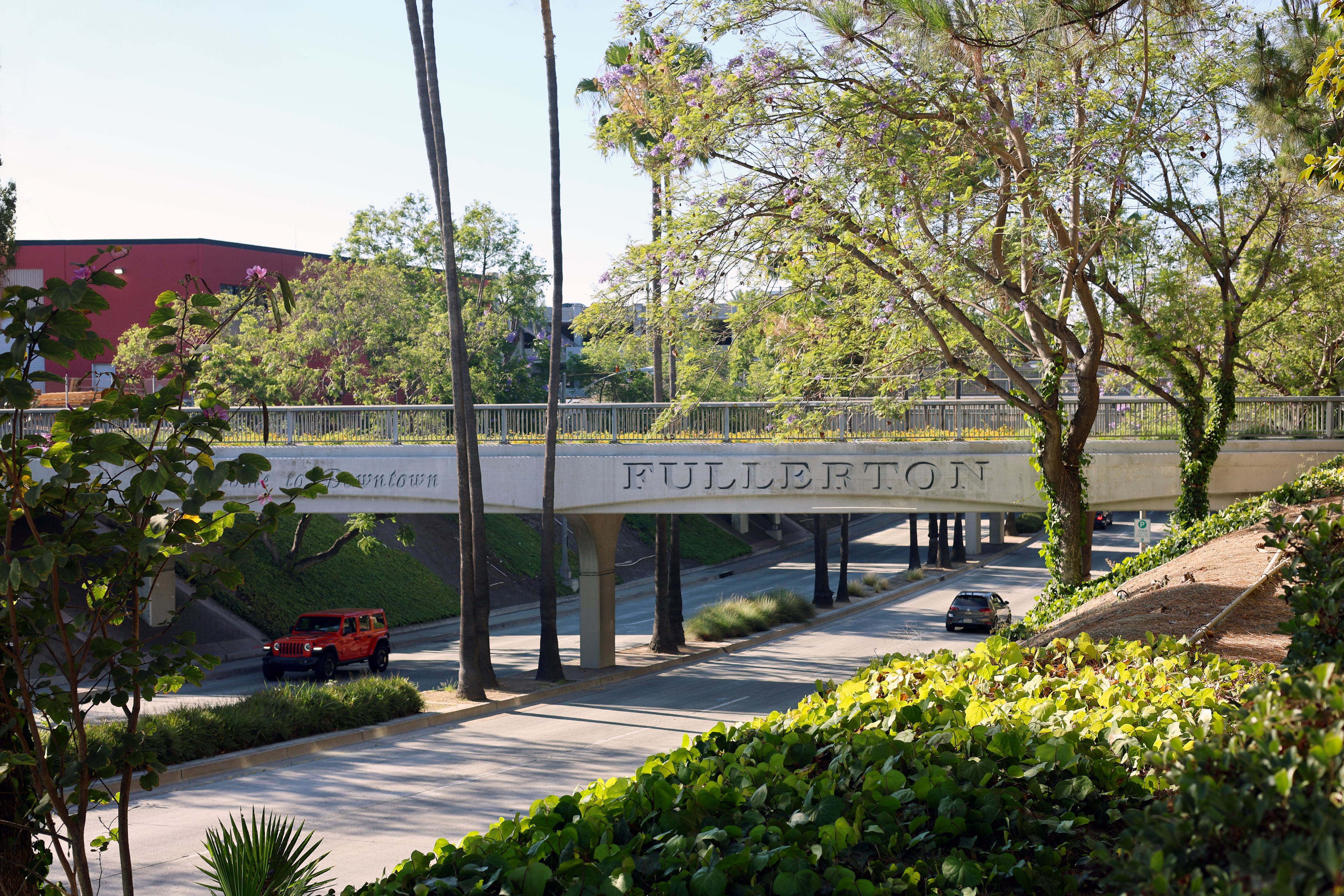 Fullerton, California, USA - Welcome Sign on Downtown Train Overpass Above Harbor Boulevard With Moving Traffic, Railroad Infrastructure and Busy Urban Streets on a Sunny Day
