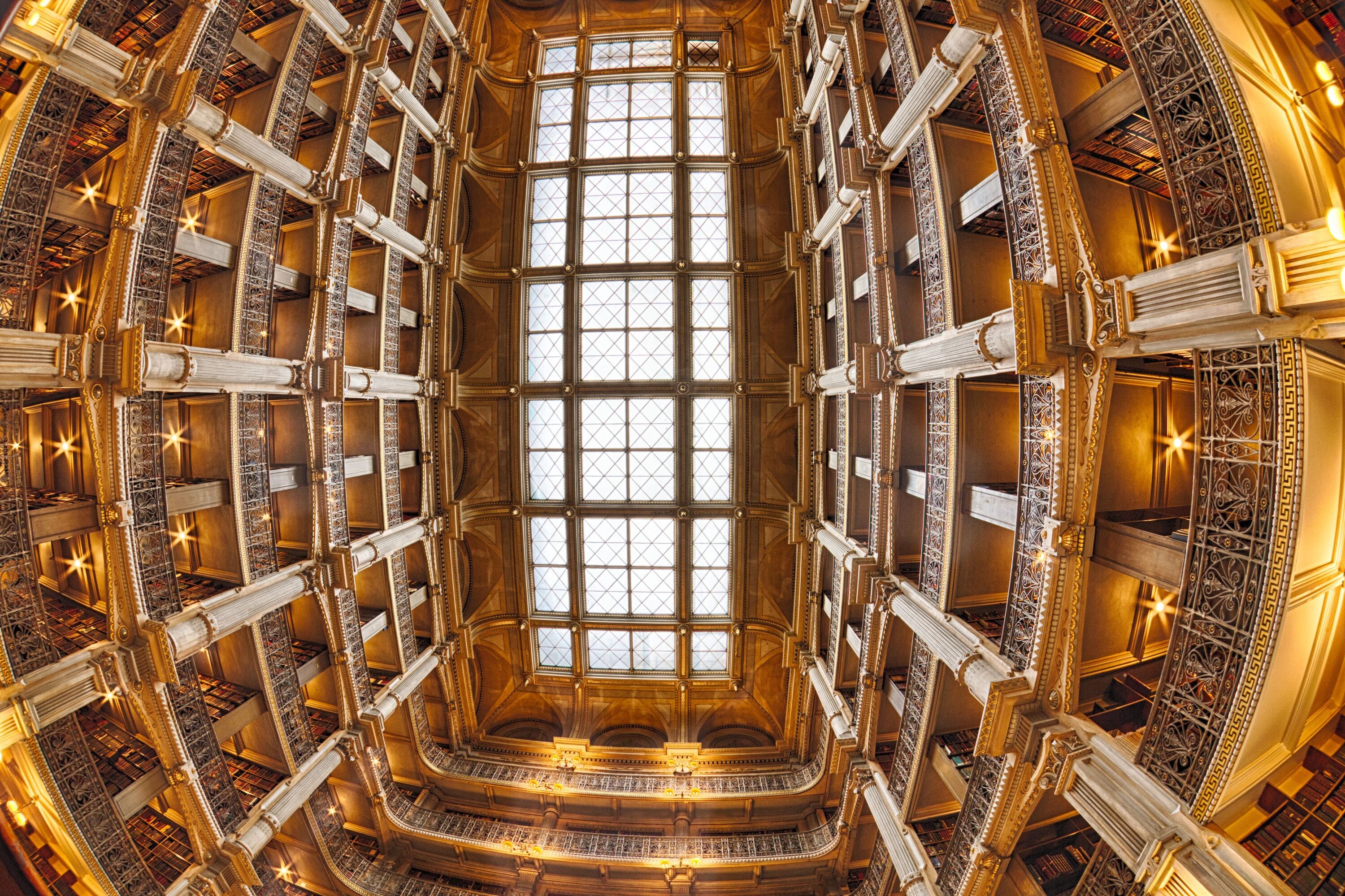 A grand, ornate library interior with a central glass window and intricate metal railings.