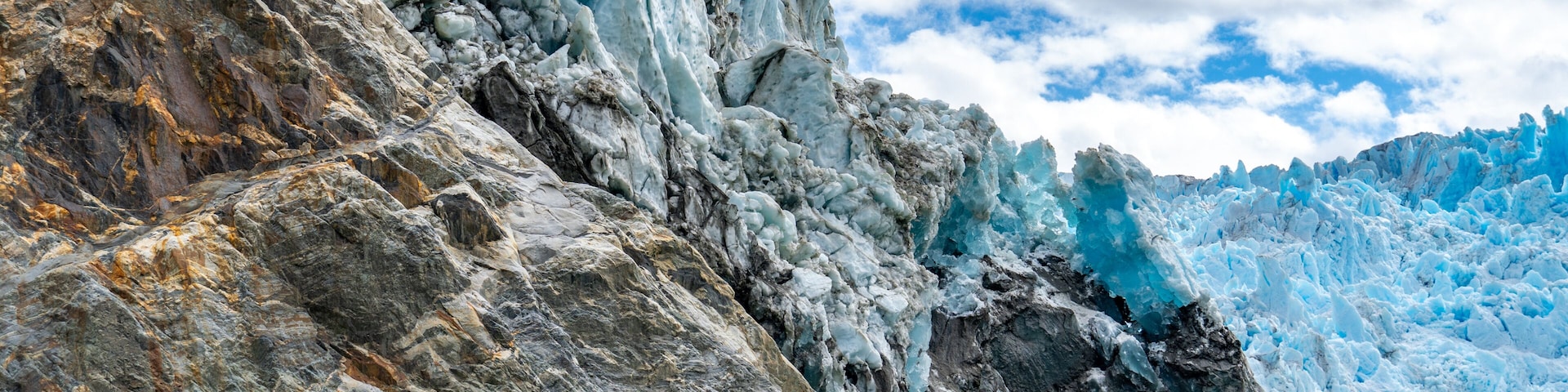 Un glaciar con formaciones de hielo afiladas y un primer plano rocoso.