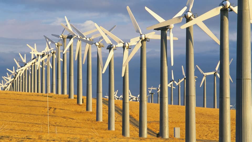 A wind farm with numerous wind turbines on a grassy hill.