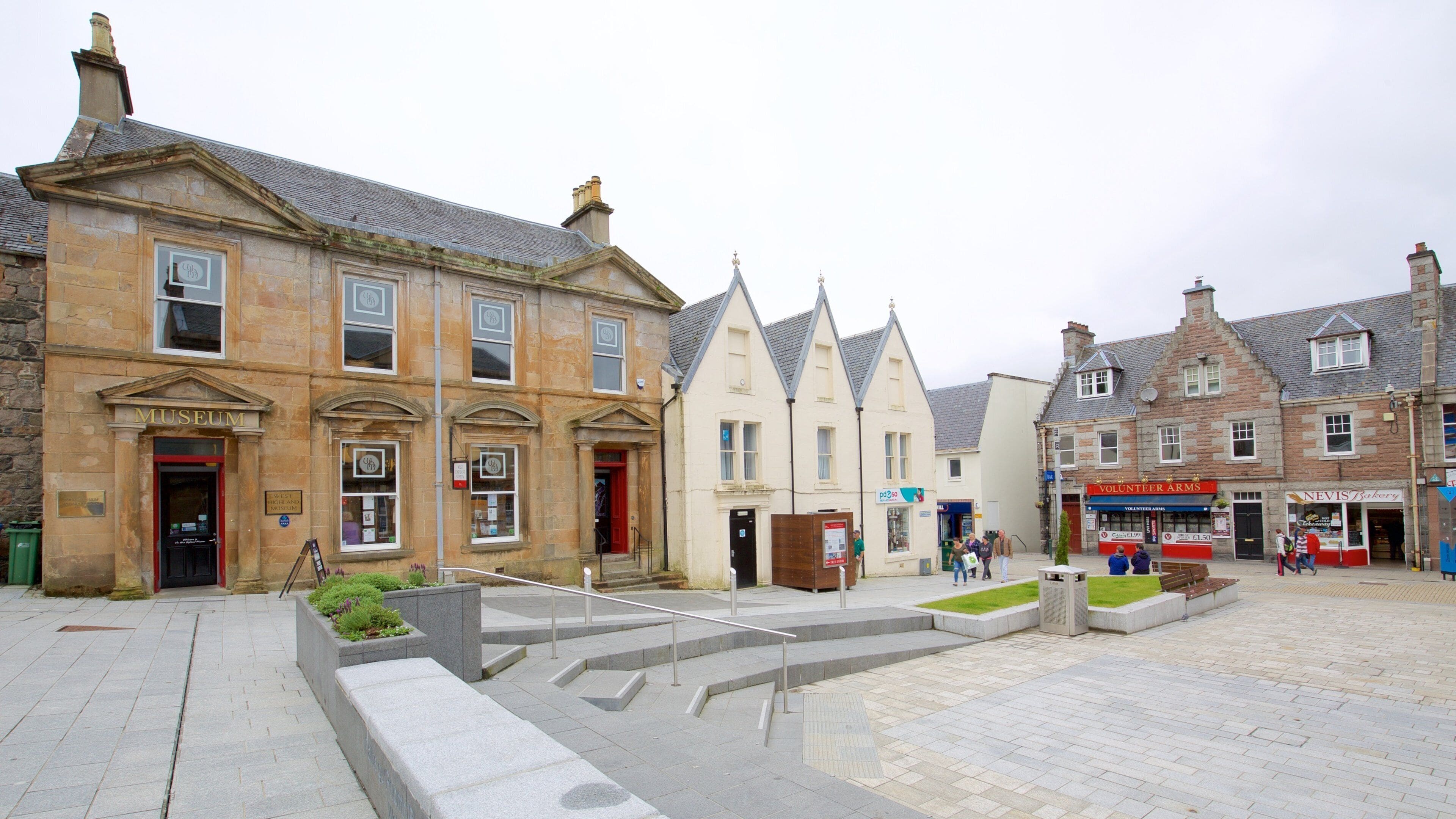 A historic street with stone buildings, a museum, and a volunteer arms shop.