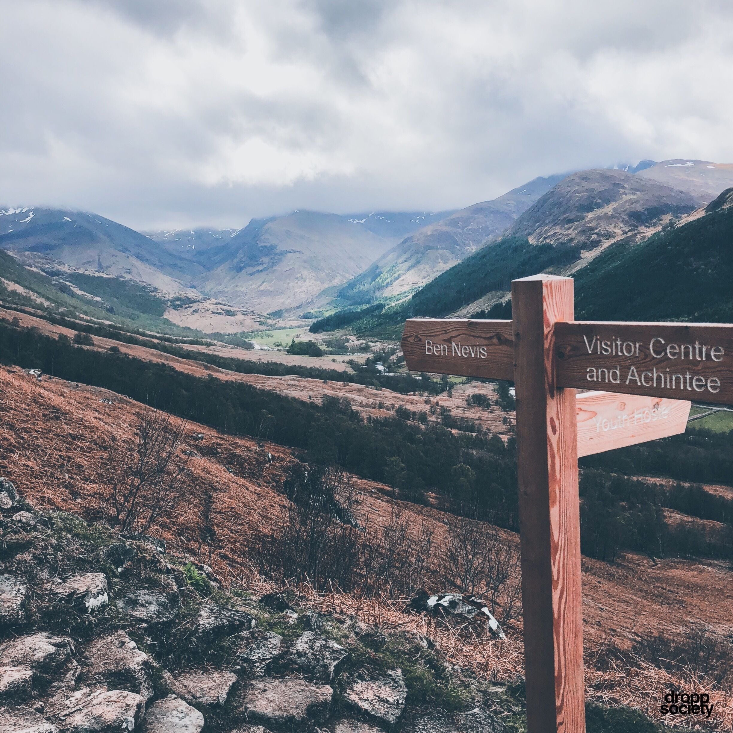 A wooden signpost with directions to Ben Nevis and Visitor Centre and Achintee.