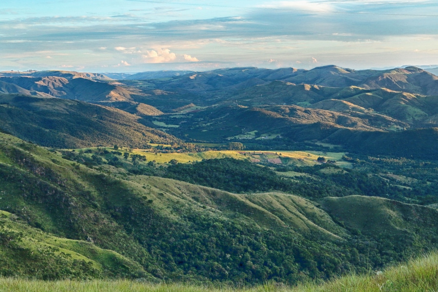 Colinas suaves, um vale e montanhas ao longe.