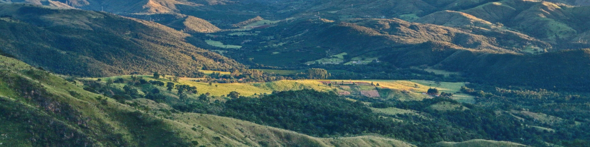 Des collines ondulantes, une vallée et des montagnes lointaines.