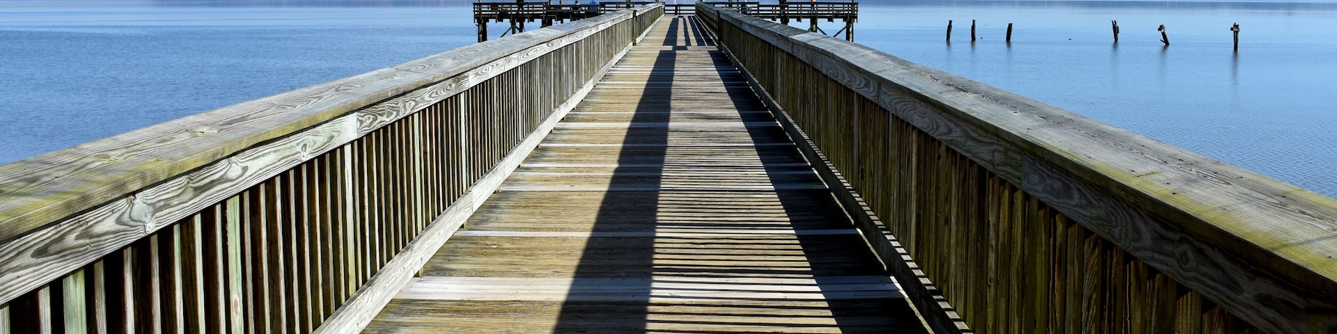 Un muelle de madera que se adentra en aguas tranquilas bajo un cielo despejado.