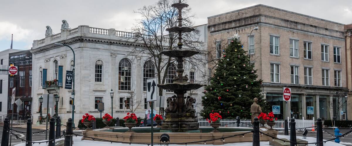 Una plaza pública con una fuente, un árbol de Navidad y edificios históricos.