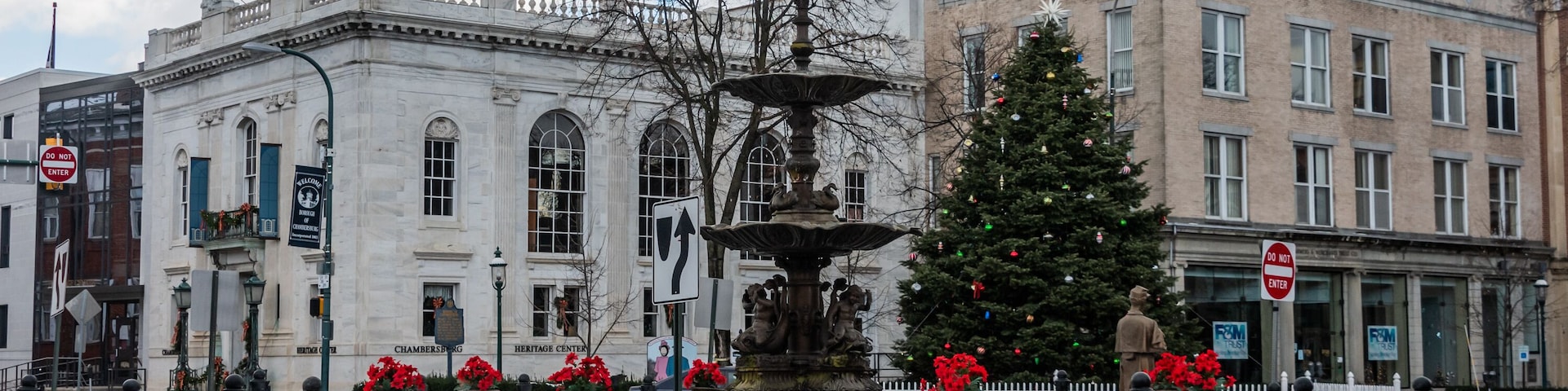 Una plaza pública con una fuente, un árbol de Navidad y edificios históricos.