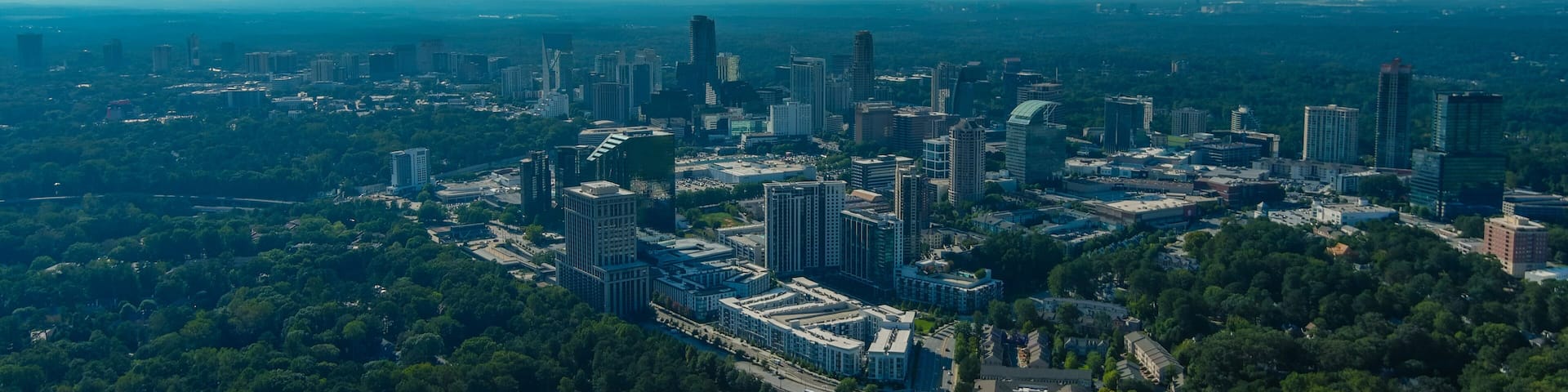 A cityscape with a rainbow, dense greenery, and a mix of modern and older buildings.