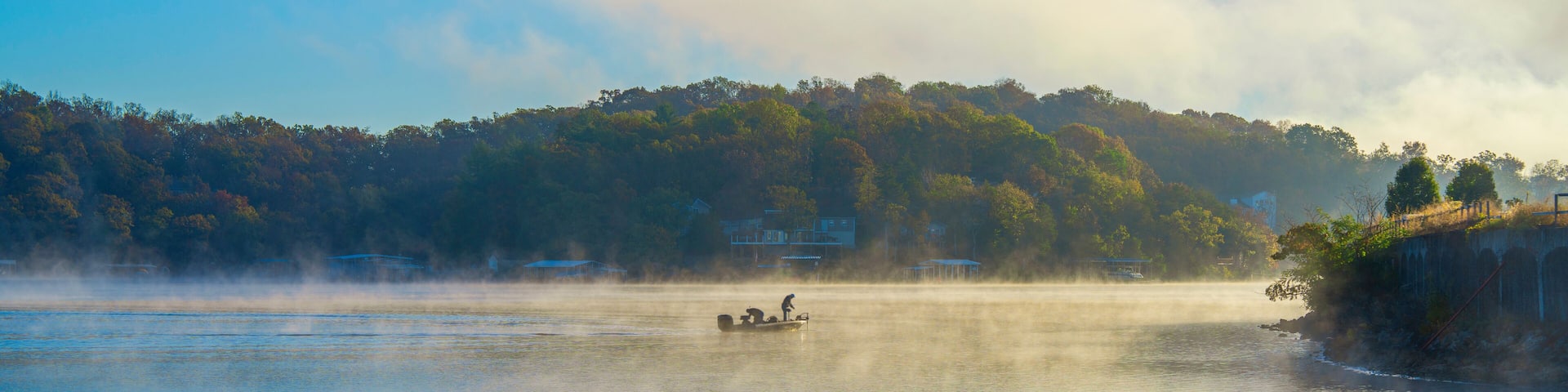 Sunrise with a fishing boat on a Foggy Morning at Lake of the Ozarks in Rocky Mount Missouri, USA