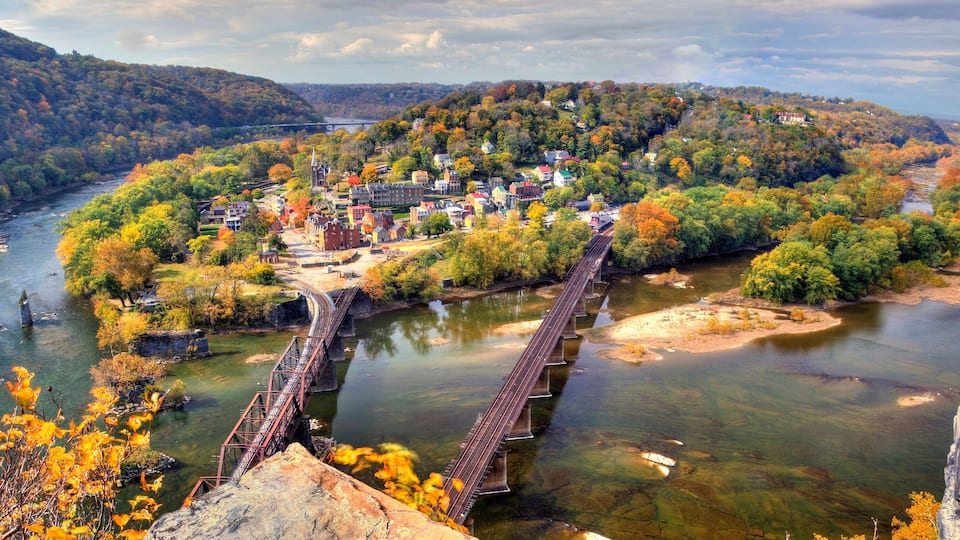 A river with a bridge, a town with historic buildings, and autumn foliage.