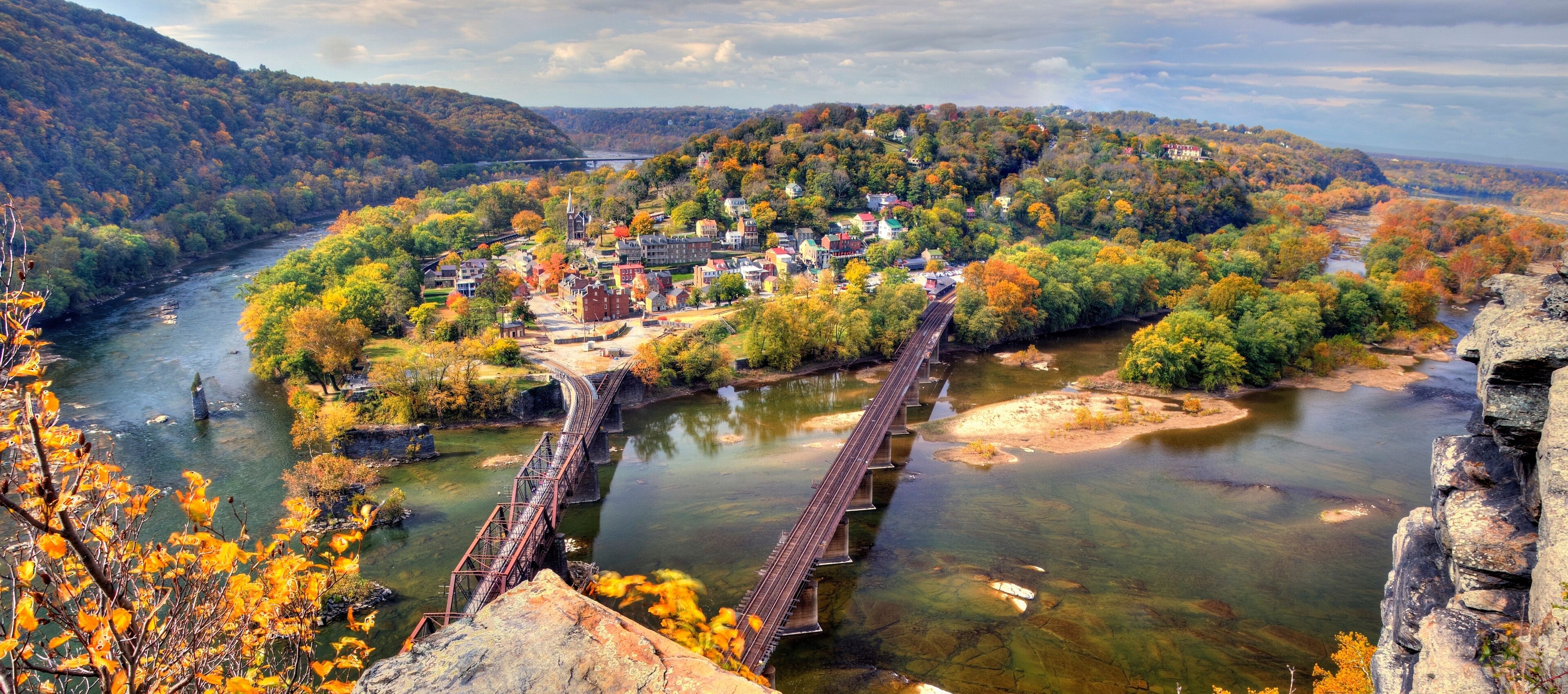 A river with a bridge, a town with historic buildings, and autumn foliage.