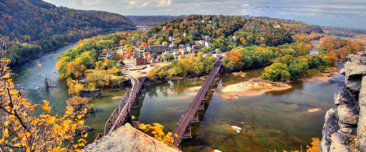 A river with a bridge, a town with historic buildings, and autumn foliage.