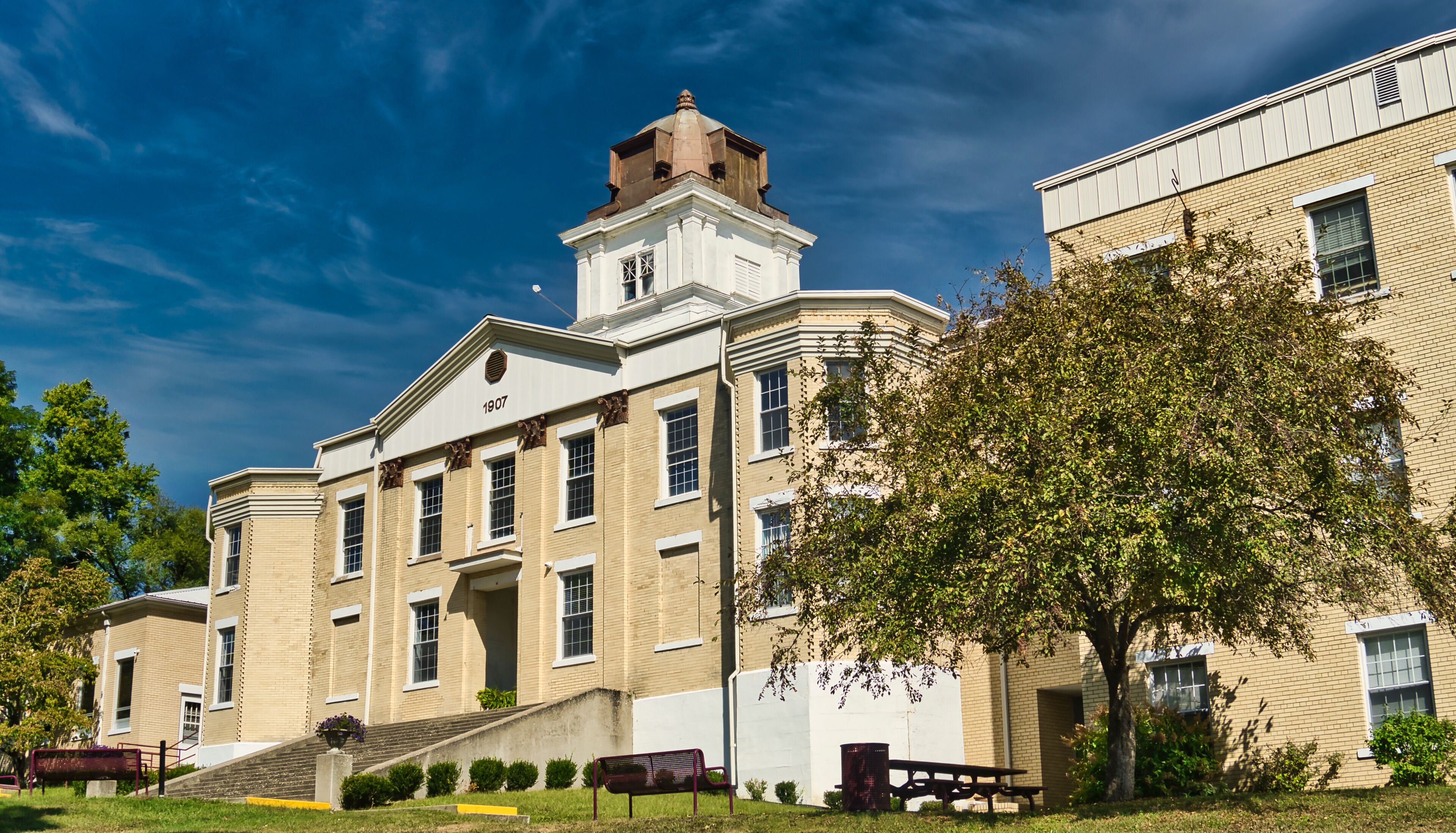 A historic building with a tower, surrounded by trees and a clear sky.