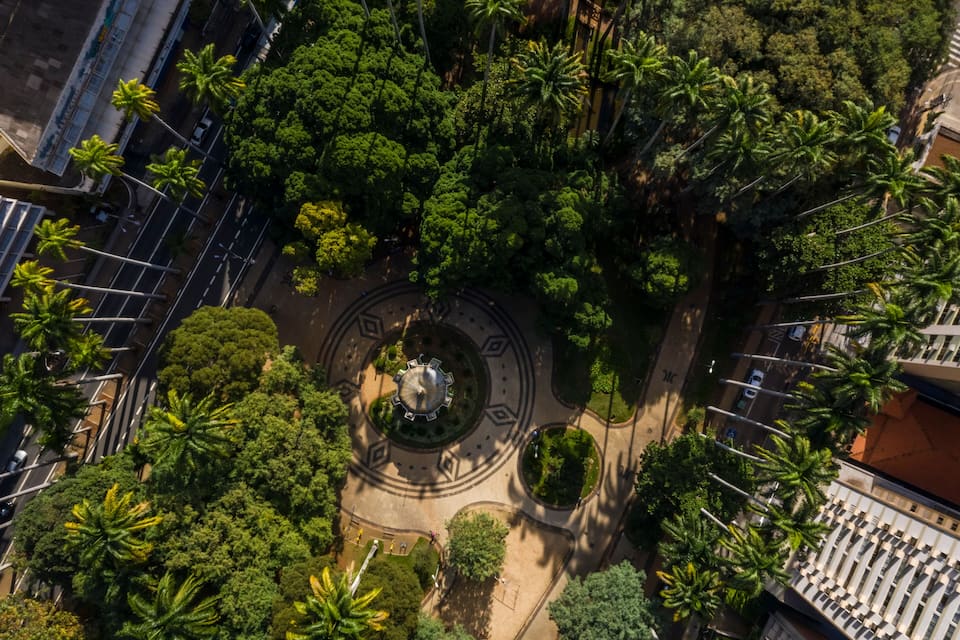 Eine Luftaufnahme eines kreisförmigen Parks mit Palmen und einem zentralen Denkmal, umgeben von Gebäuden.