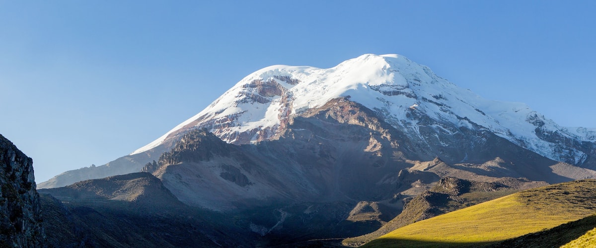 A snow-capped mountain with rocky slopes and a valley.